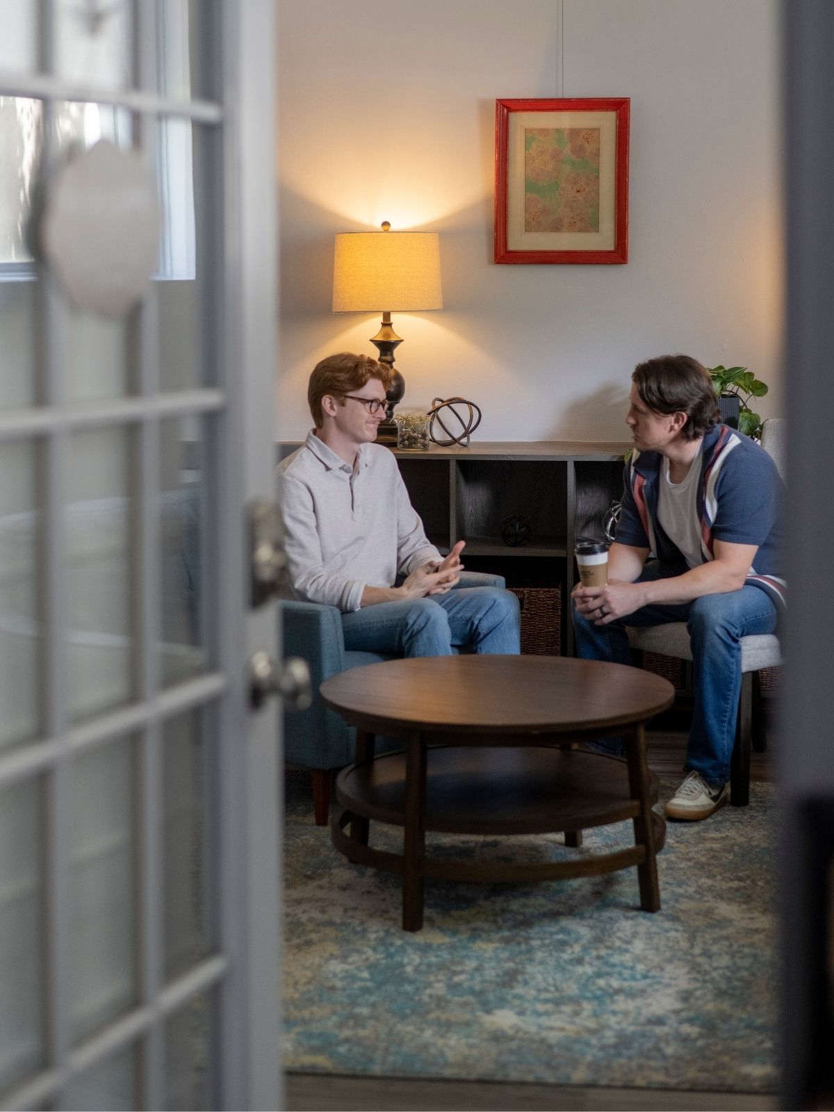 A counselor sits in a comfortable office setting, attentively engaging with a small group during a discussion or support session. The warm, welcoming environment fosters connection, open communication, and personal growth.