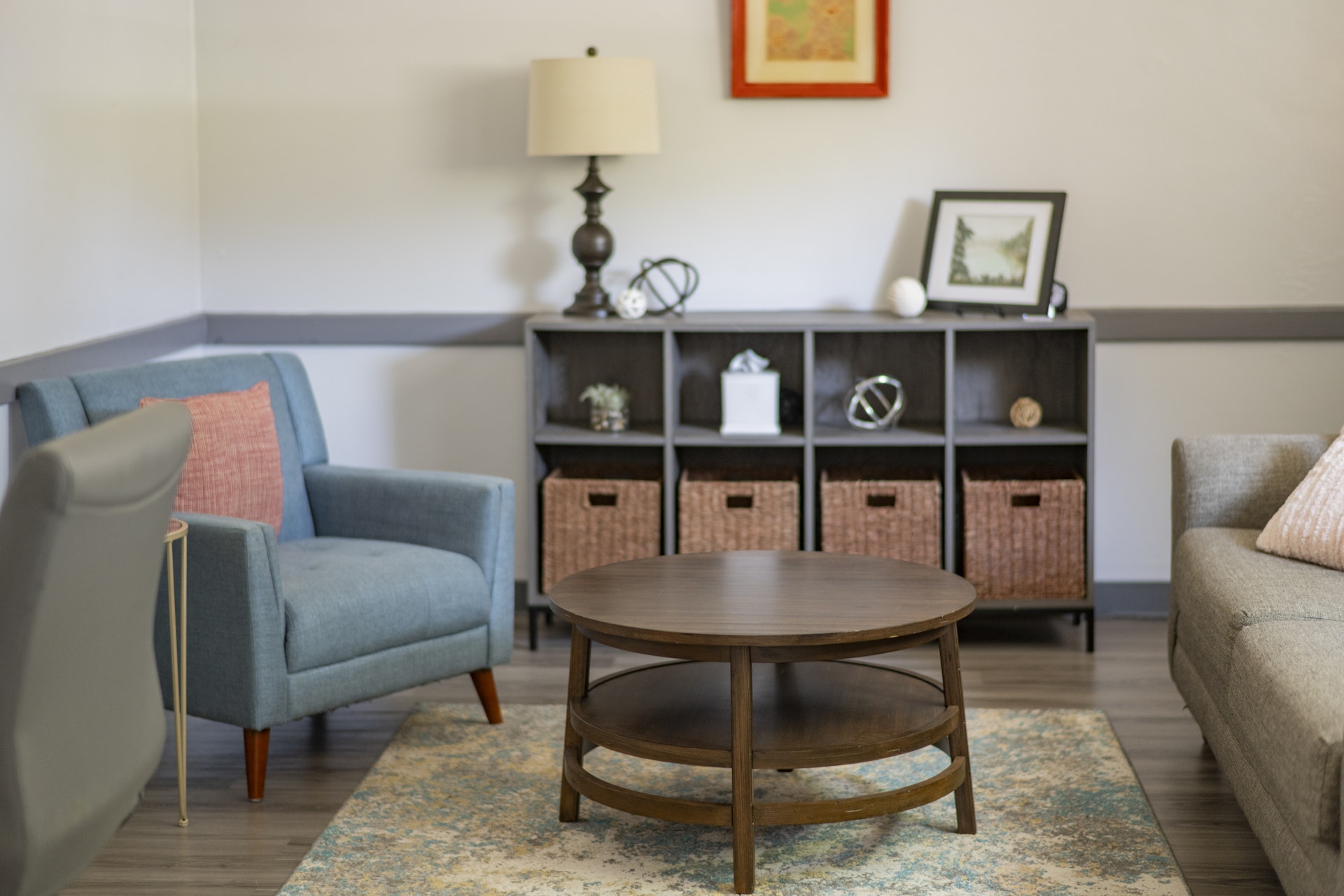 Comfortable counseling office featuring upholstered chairs, a sofa, and a round coffee table arranged to encourage conversation. The welcoming space includes soft lighting, decorative accents, and a calm, professional atmosphere.